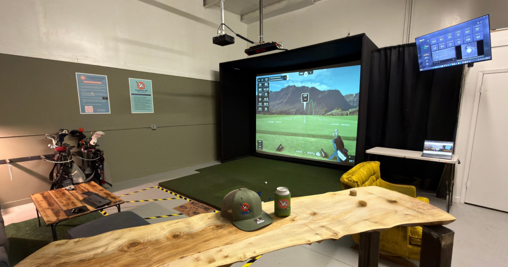 Golfer mid-swing inside the Albatross Indoor Golf simulator bay in Boise