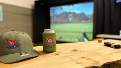 Photo of an Albatross Indoor Golf hat and koozie at the Albatross Indoor Golf simulator in Boise.